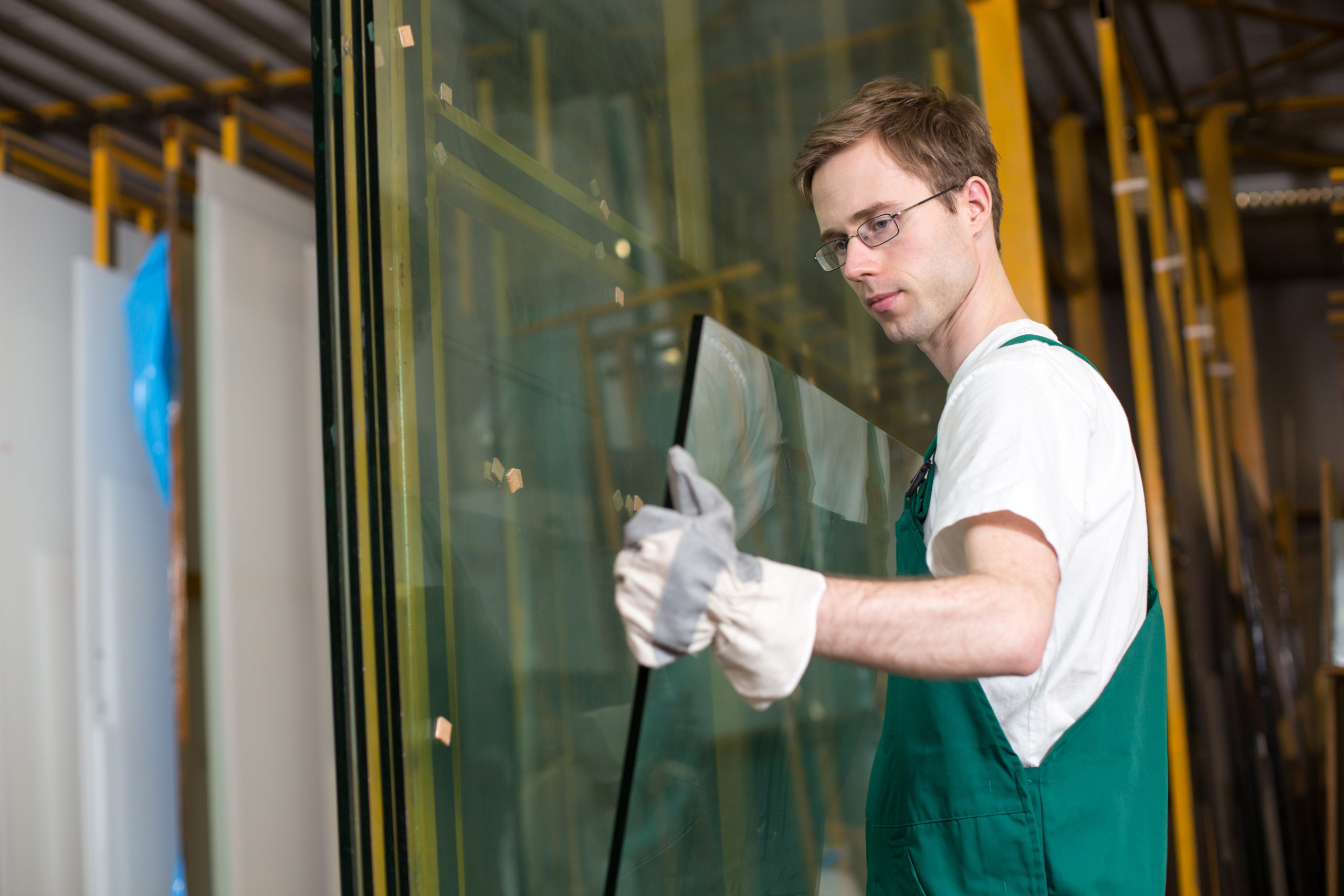 Worker in glazier's workshop, warehouse  or storage handling glass